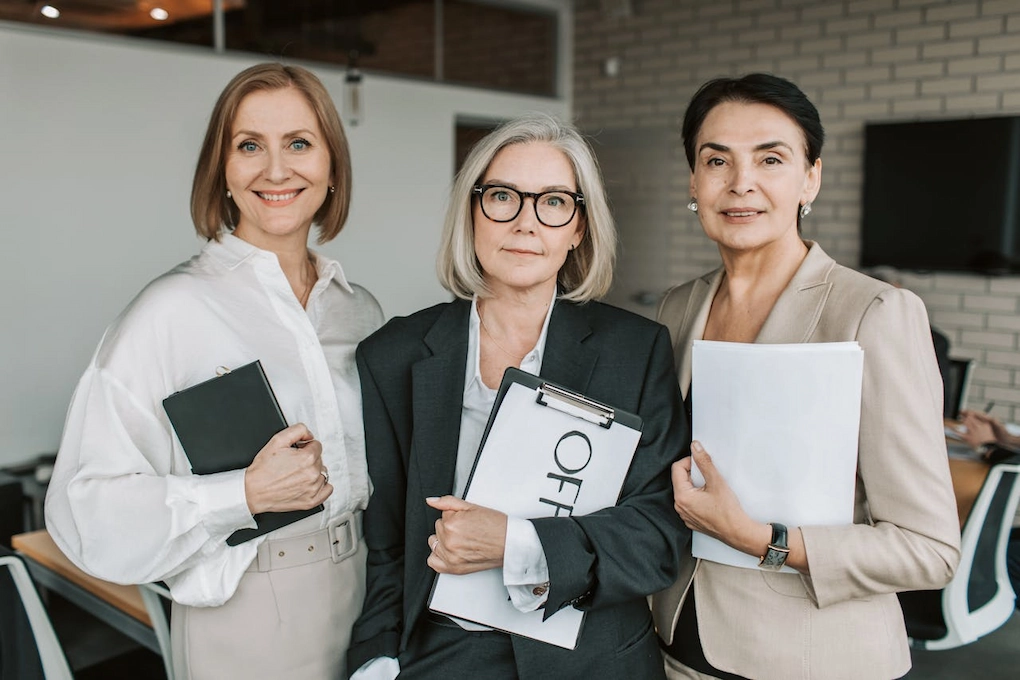 Three women standing together in a business setting. Funding resources for women in Massachusetts.