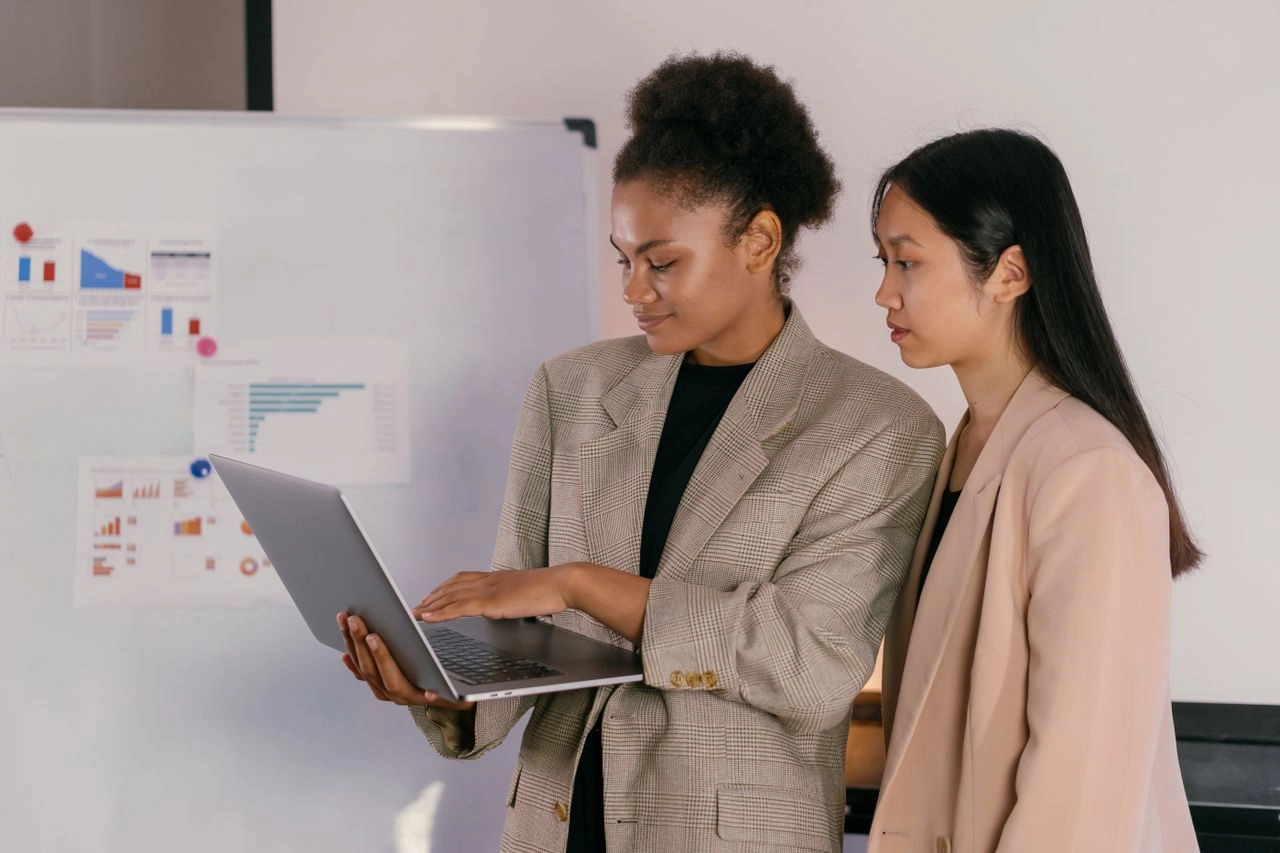 Two women staring at a laptop in an office. What funders mean by business impact