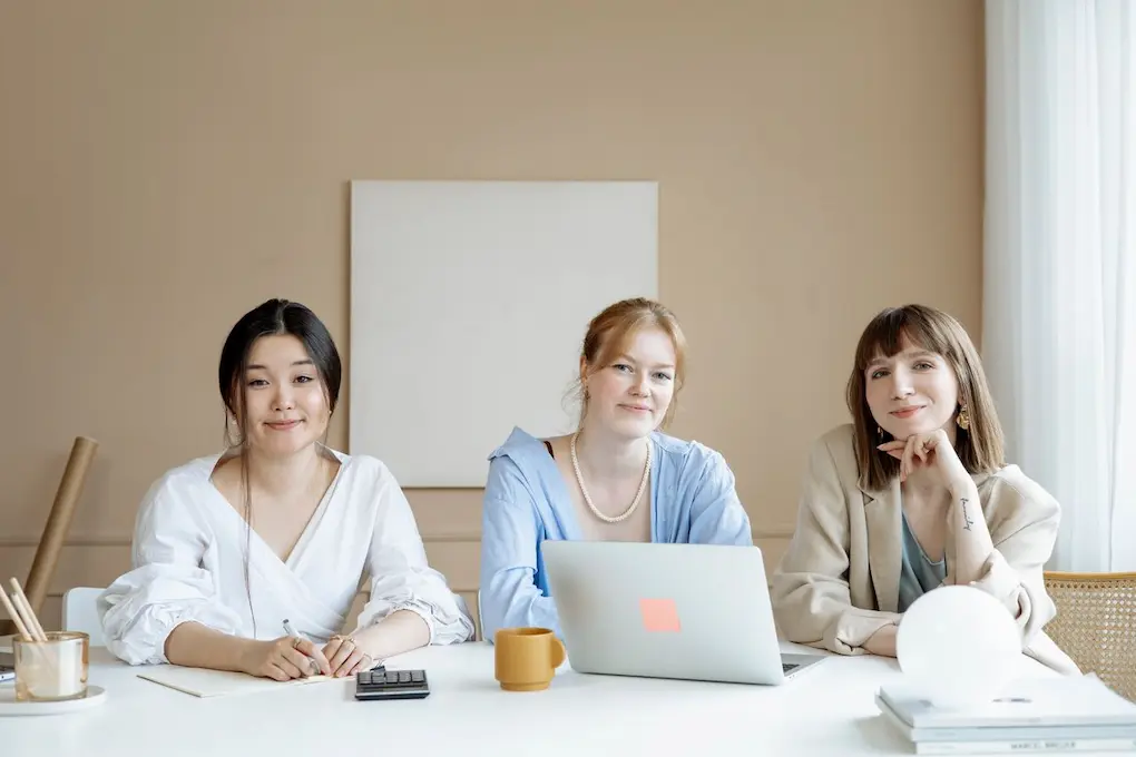 Three women working together at a desk. Fund Her Future Grant