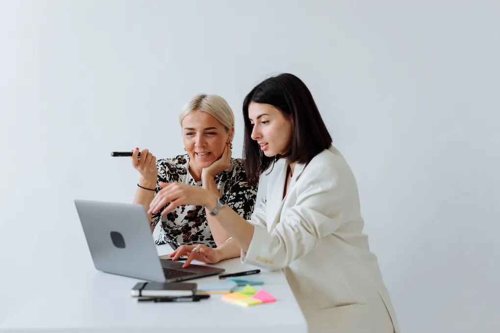 Two women engaging in a business discussion over a laptop. Business Grants and Resources for women in North Dakota