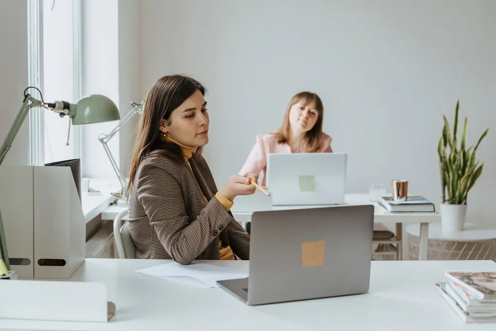 Two women discussing business in a modern office. Business Grants and Resources for Women in Idaho.